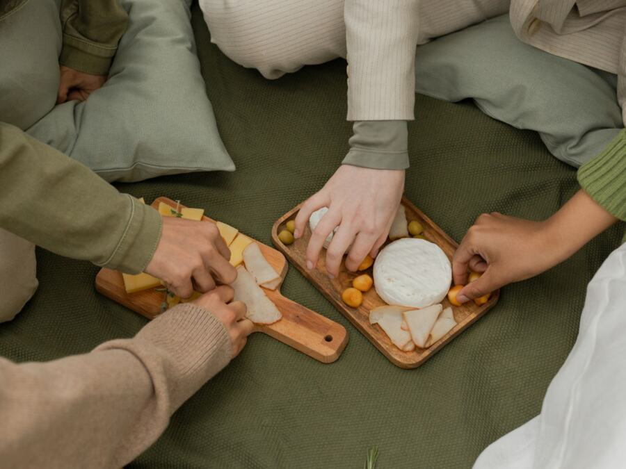 Friends sharing cheese on a board at a picnic