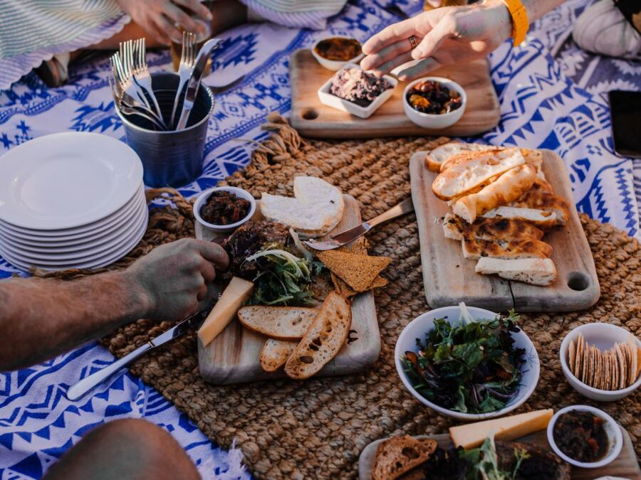 A picnic spread of bread, cheese, salad and snacks on a patterned cloth